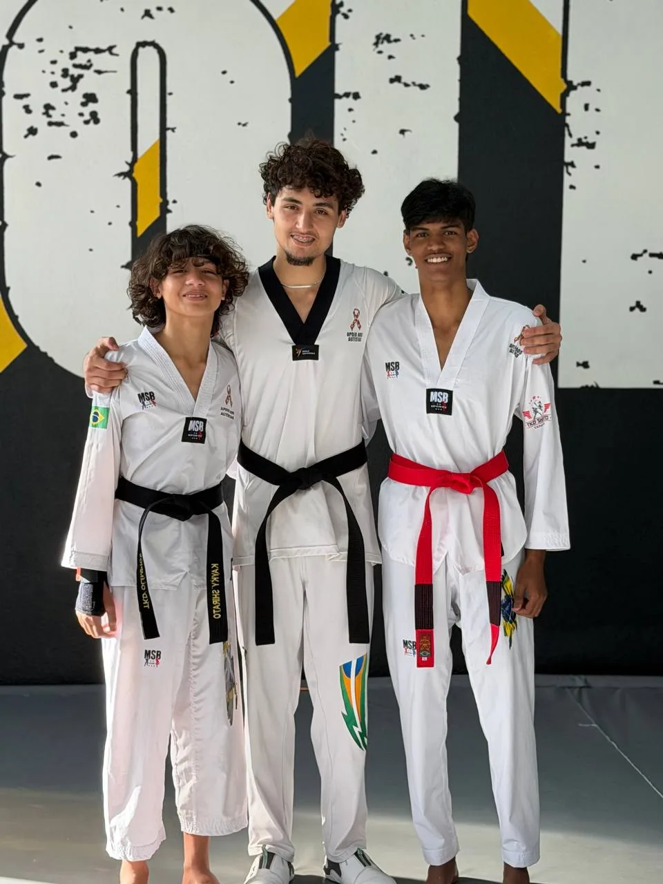 Três atletas do Instituto de dobok, faixas preta e vermelha
