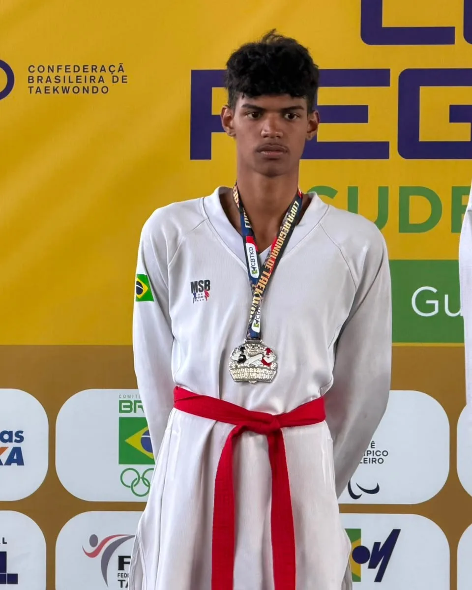 Pedro Coelho no pódio de competição da CBTKD, de faixa vermelha e com a medalha no pescoço